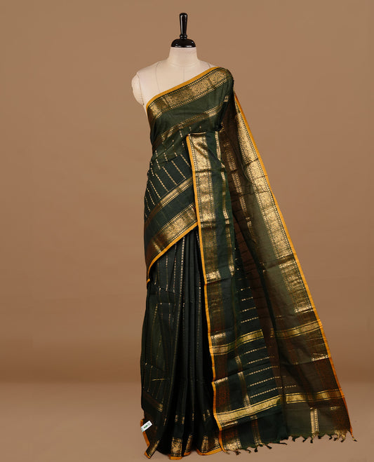 Dark green colour chettinad cotton saree featuring gold zari stripes on body, complemented by self colour with zari  mustard piping border, paired with matching blouse piece.