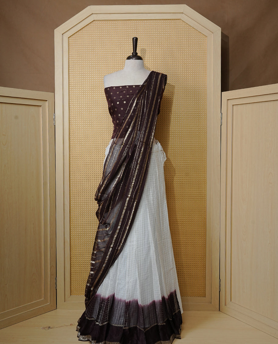 Off white colour Semi stitched dhavani set featuring Gold zari check pattern with contrast Chocolate colour border skirt, paired with matching blouse & dupatta.