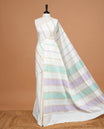 Cream Colour Cotton Kerala Saree Featuring Green & Light Purple Strips On The Body & Pallu, Paired With A Matching Blouse Piece.