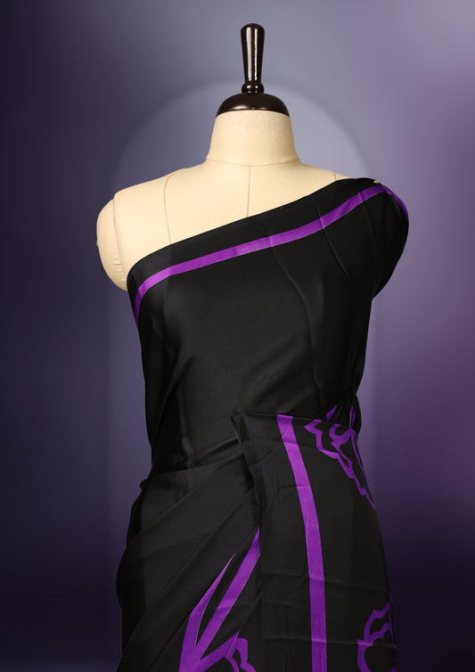 Black colour saree featuring bold floral motifs in deep purple, enhanced with matching striped borders and a contemporary patterned pallu, paired with a coordinating blouse.