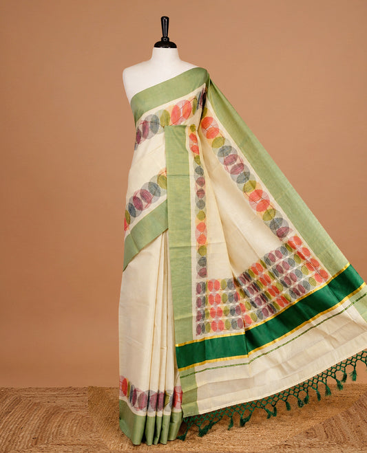 Cream Colour Tissue Kerala Saree Featuring Multicolour Circular Prints Along The Border And Pallu, Complemented By A Light Green Border With Traditional Gold Zari Accents, Paired With A Matching Blouse Piece.