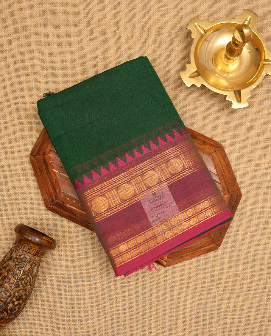 Dark green colour chettinad cotton saree featuring Elegant plain body, contrast Meganta colour border with gold zari chakra and temple border, pallu and paired with matching blouse.