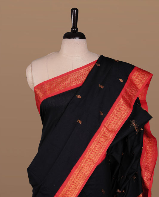 Black colour kalyani cotton saree featuring antique zari motifs on body, complemented by red colour with Antique zari border, paired with matching blouse piece.