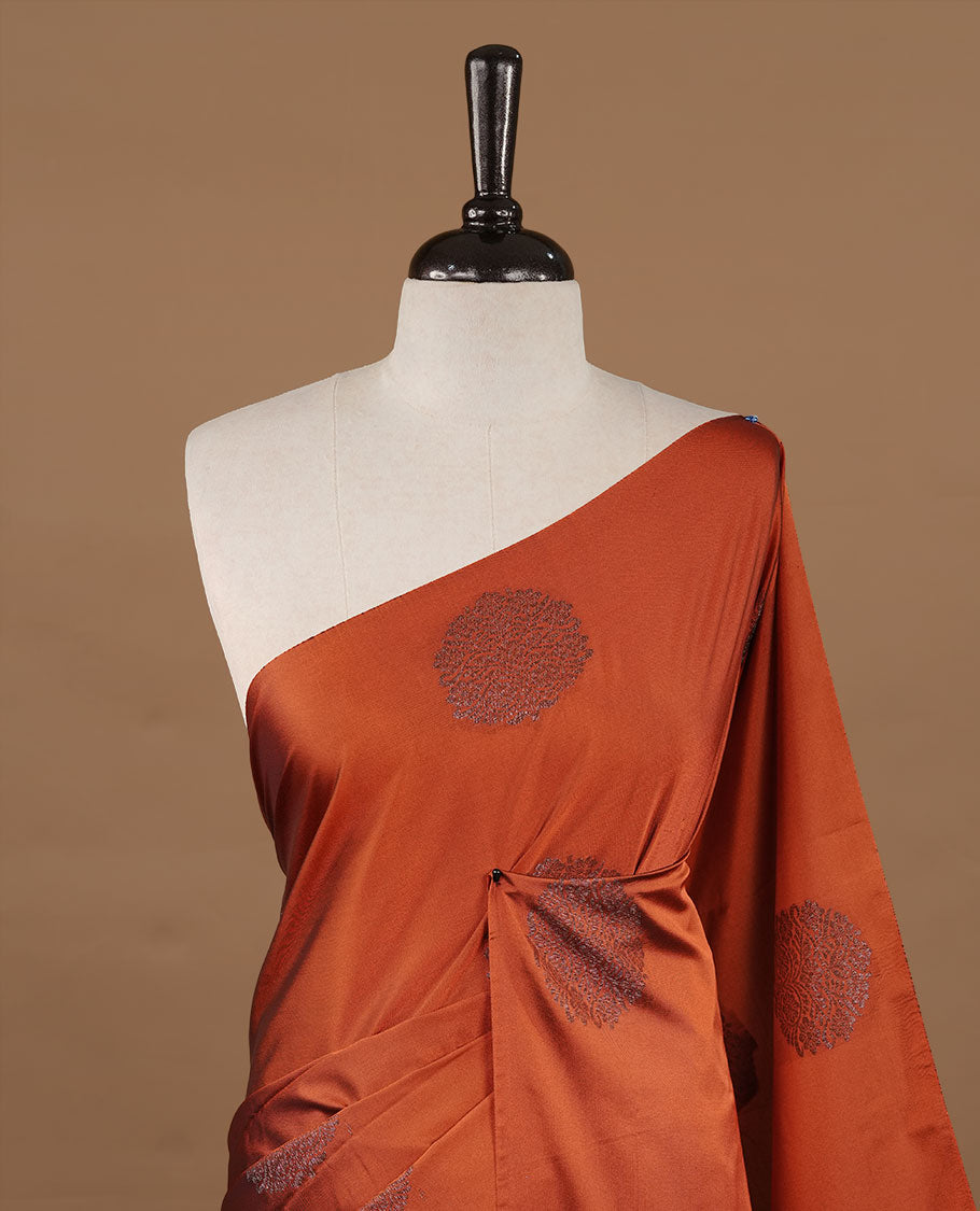 Rust orange colour soft silk saree features a sleek borderless design with intricate antique zari motifs, flowing into a striking contrast Black berry pallu and a matching blouse piece.