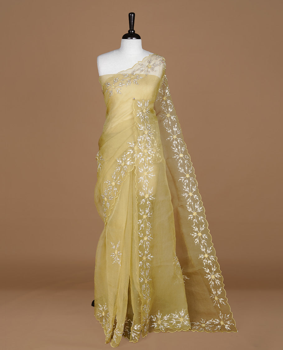 Pastel olive colour crush organza saree featuring gold thread floral and stone worked body, highlighting scalp designed border, paired with matching blouse piece.