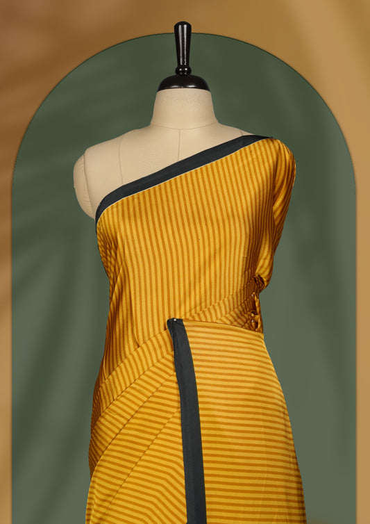 Mustard yellow colour striped saree with a bold black border and geometric pallu featuring a Madhubani style motif and paired with blouse.