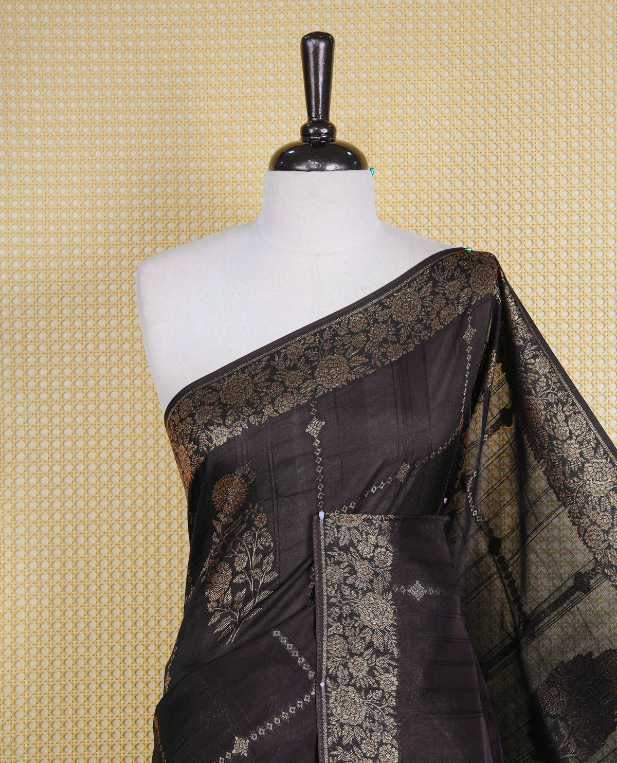 Black colour semi banaras tussar georgette saree featuring gold zari floral pattern on body, finished with gold zari floral motifs on border and paired with matching blouse piece.