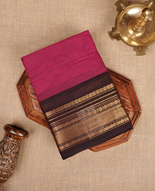 Magenta colour chettinad cotton saree featuring plain body, contrast brown colour with traditional gold zari border paired with matching blouse.