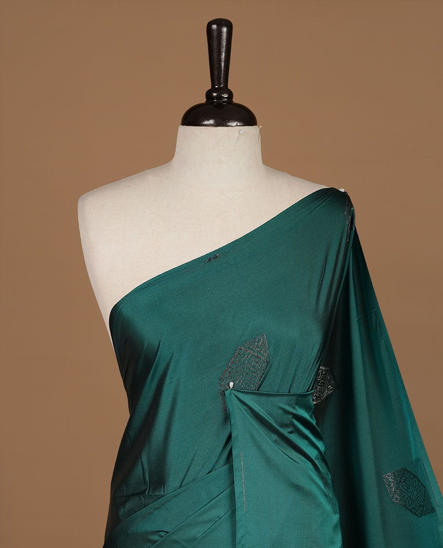Teal green soft silk saree features a sleek borderless design with intricate antique zari motifs, flowing into a seamless self colored pallu and a matching blouse piece.