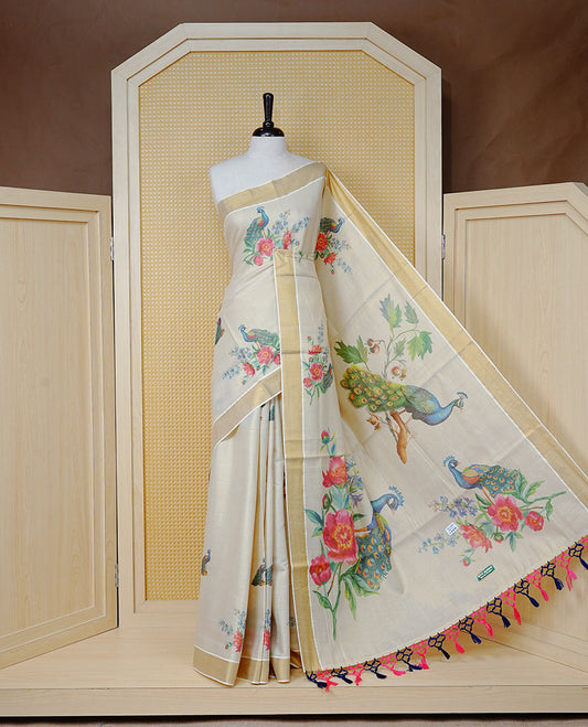 Cream Colour Tissue Kerala  Saree Featuring A Digital  Peacock & Floral Printed Body &  Pallu ,  Beautifully Enhanced With A Classic Gold Zari Border And  Blue & Baby Pink Tassels, Paired With A Matching Blouse Piece