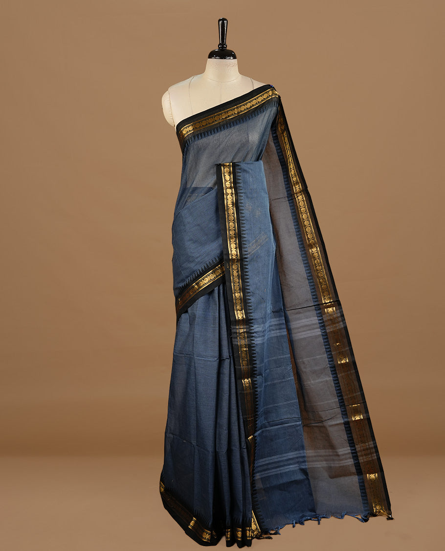 Bluish grey colour chettinad cotton saree featuring elegant plain body, complemented by black colour with zari border, paired with matching blouse piece.