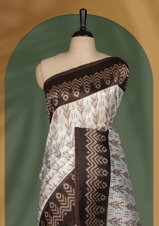 Classic off white colour saree adorned with intricate brown tribal motifs and rich woven patterns on the pallu and border & Paired with matching blouse.