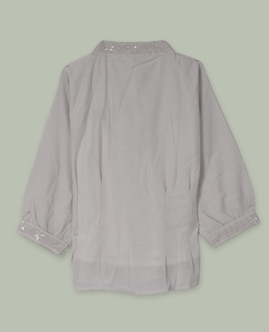 Cream three-quarter sleeve shirt top with embellished band collar and cuffs, front button placket, and soft pleating below the placket.
