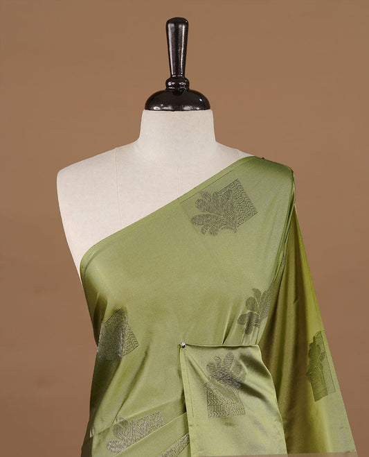 Olive colour soft silk saree features a sleek borderless design with intricate antique zari motifs, flowing into a striking contrast red pallu and a matching blouse piece.