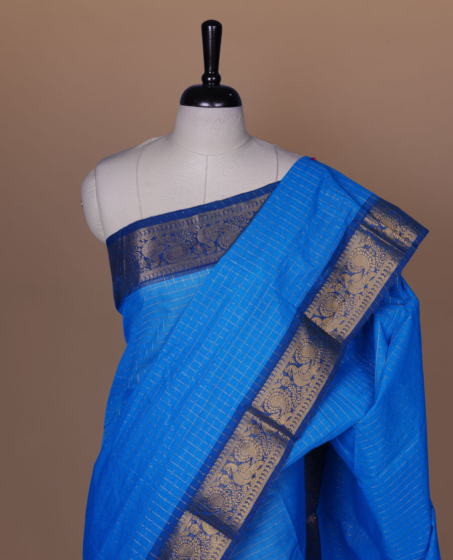 Sky blue colour sungudi cotton saree featuring gold zari check pattern across body, contrast Dark blue colour with gold zari peacock and floral pattern on border, without blouse piece.
