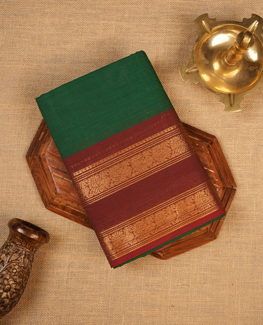 Dark green colour chettinad cotton saree featuring elegant plain body highlighting contrast maroon colour colour with gold zari traditional border, pallu and paired with matching blouse piece.