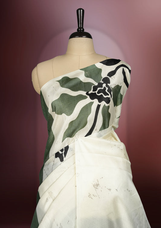 Olive green and off white colour saree with bold black floral prints enhancing its modern charm & Crafted from soft, lightweight fabric for elegant draping, this saree comes paired with a matching blouse piece.