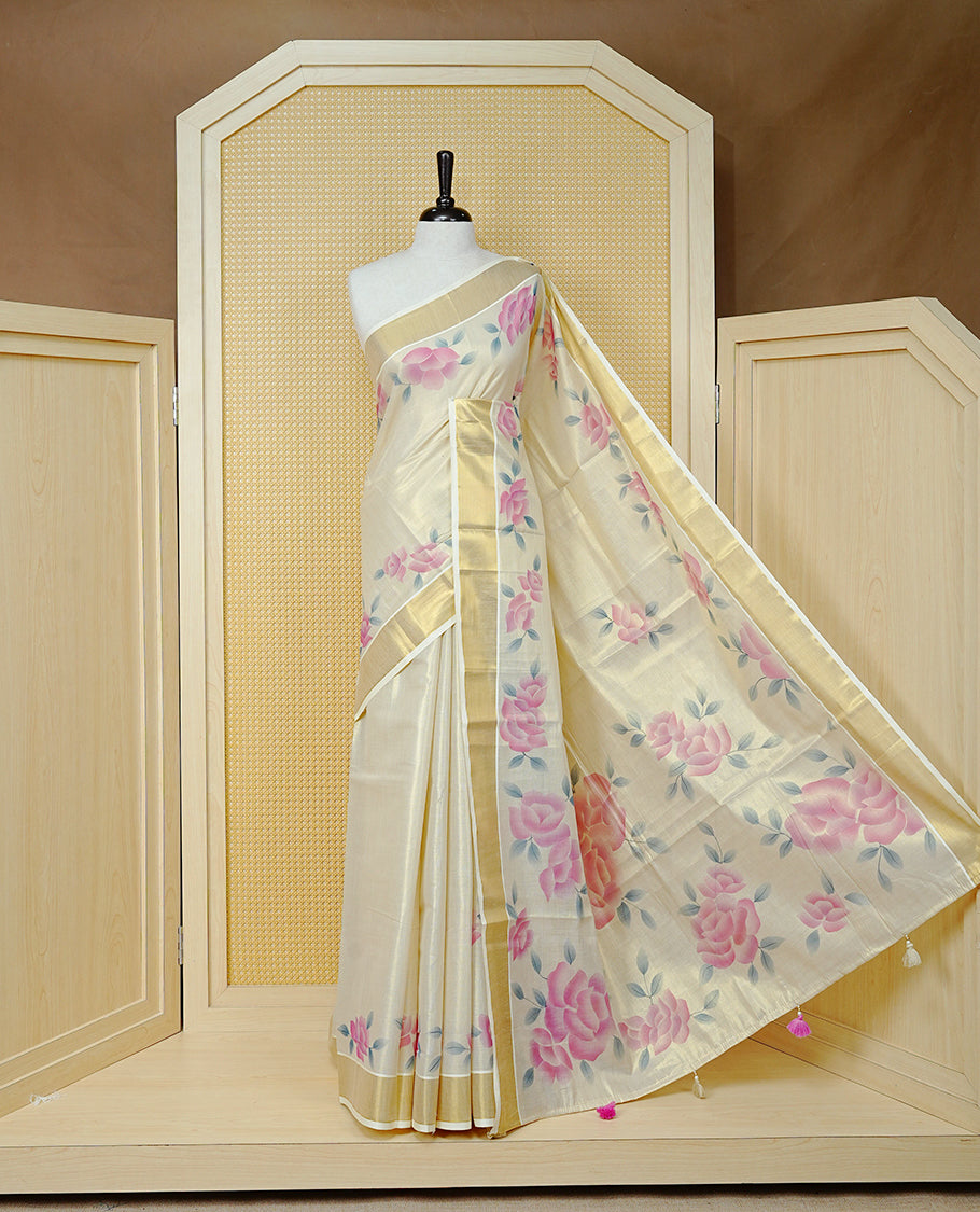 Cream Colour Tissue Kerala Saree Featuring Digital  Pink Rose Prints Across The Body, Enhanced With A Gold Zari Border , Finished With Pink & Cream Tassels And A Matching Blouse Piece