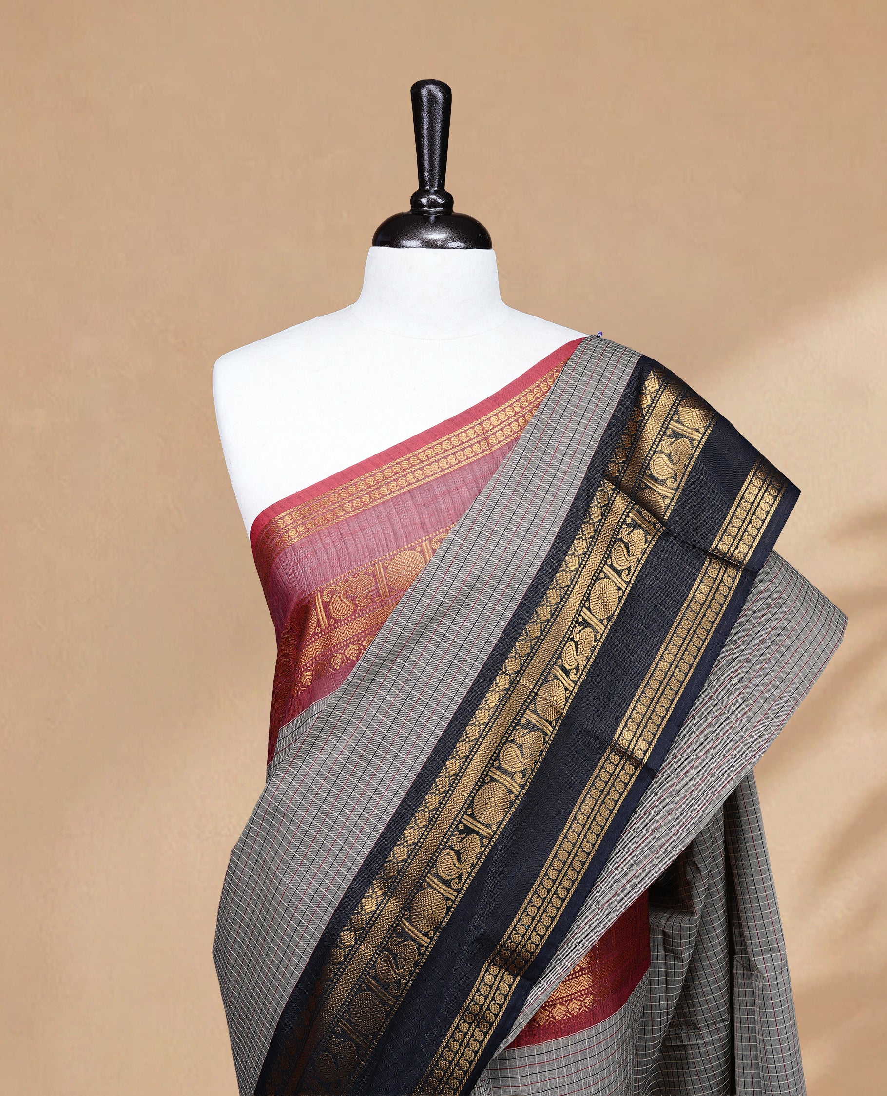 Grey colour chettinad saree featuring Cream colour check pattern on body, complemented by contrast black colour with Gold zari border, paired wih matching blouse piece.