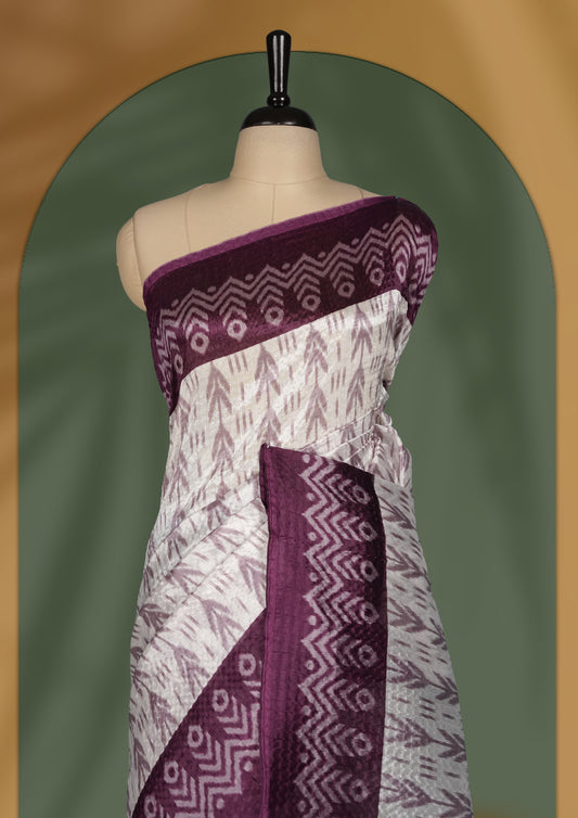 Classic off white colour saree adorned with intricate grape colour tribal motifs and rich woven patterns on the pallu and border & Paired with matching blouse.