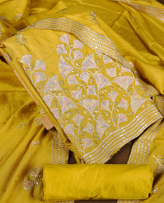 warm olive colour churidar material with subtle mirror and thread embroidery, finished with delicate border detailing and paired with a matching plain bottom and dupatta.