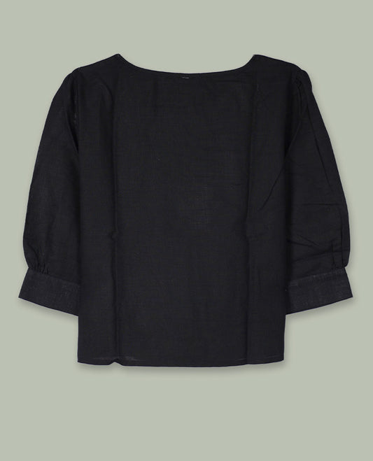 Black three-quarter sleeve top with round neckline and tonal crochet floral appliqués placed at the center front and near the hem.
