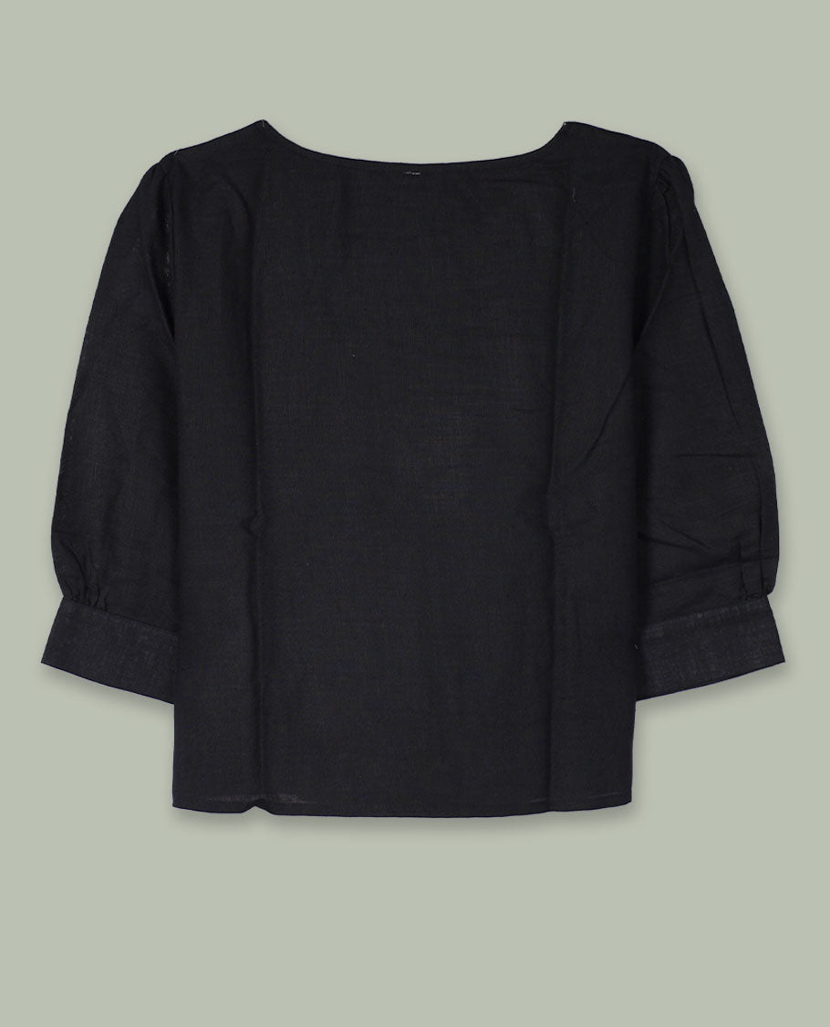 Black three-quarter sleeve top with round neckline and tonal crochet floral appliqués placed at the center front and near the hem.