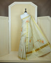 Light gold colour tissue Kerala saree featuring Floral print & Gold zari check on body, complemented by gold Border, comes with matching blouse piece.