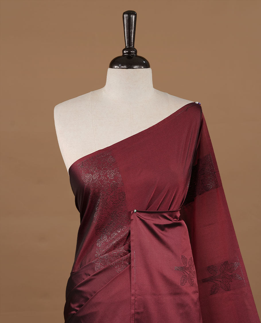 Maroon soft silk saree features a sleek borderless design with intricate antique zari motifs, flowing into a seamless self colored pallu and a matching blouse piece.