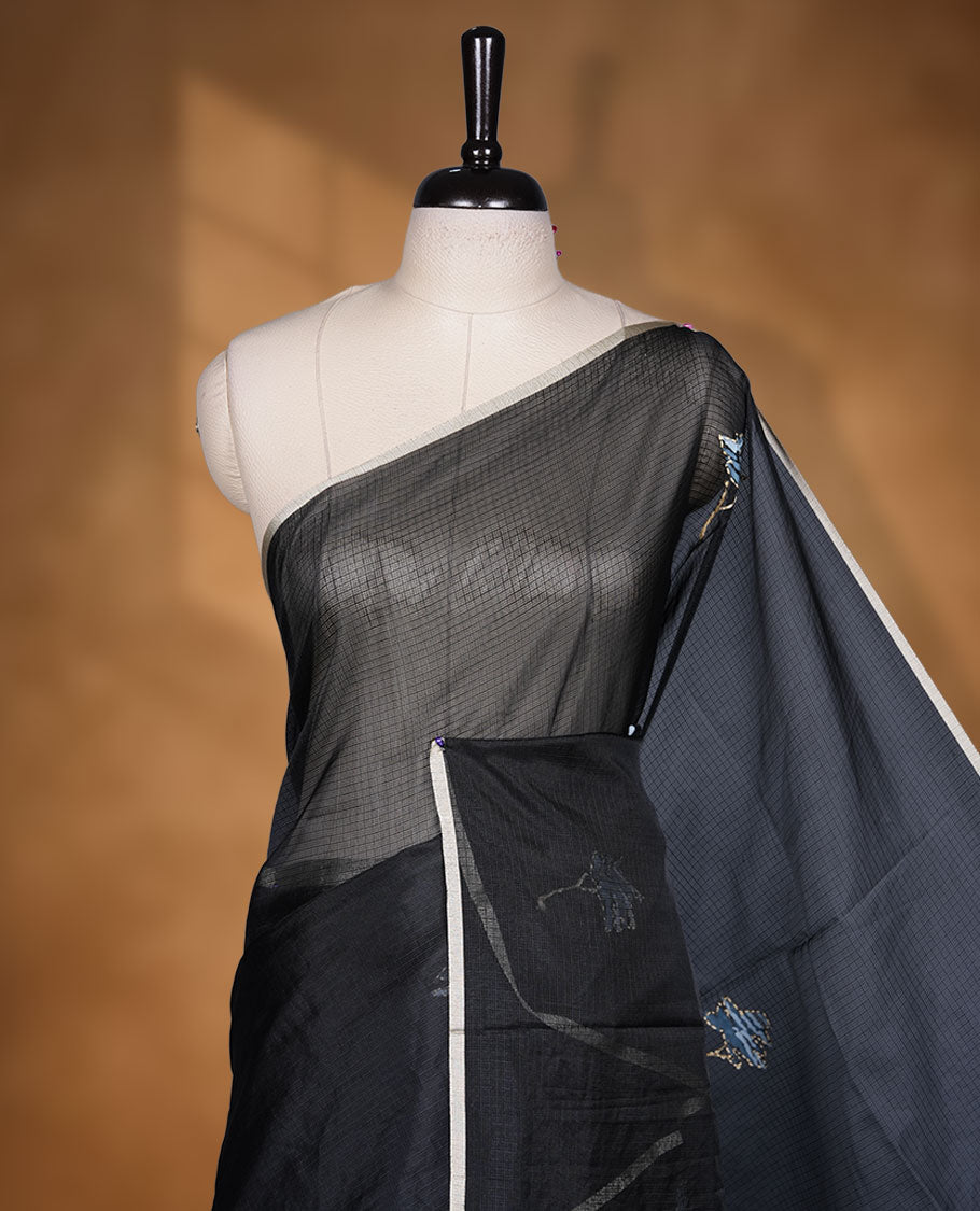 Black colour semi tusser silk saree featuring refined floral embroidery across the body, enhanced with gentle contrast border detailing and accompanied by a perfectly matching embroidered blouse.