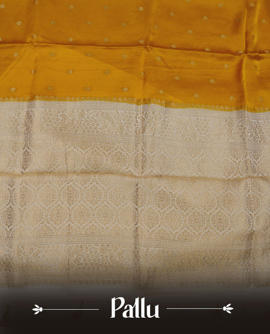 Yellow colour banaras satin crepe saree featuring gold zari motifs on body, with contrast cream colour border with gold zari pattern and paired with matching blouse.