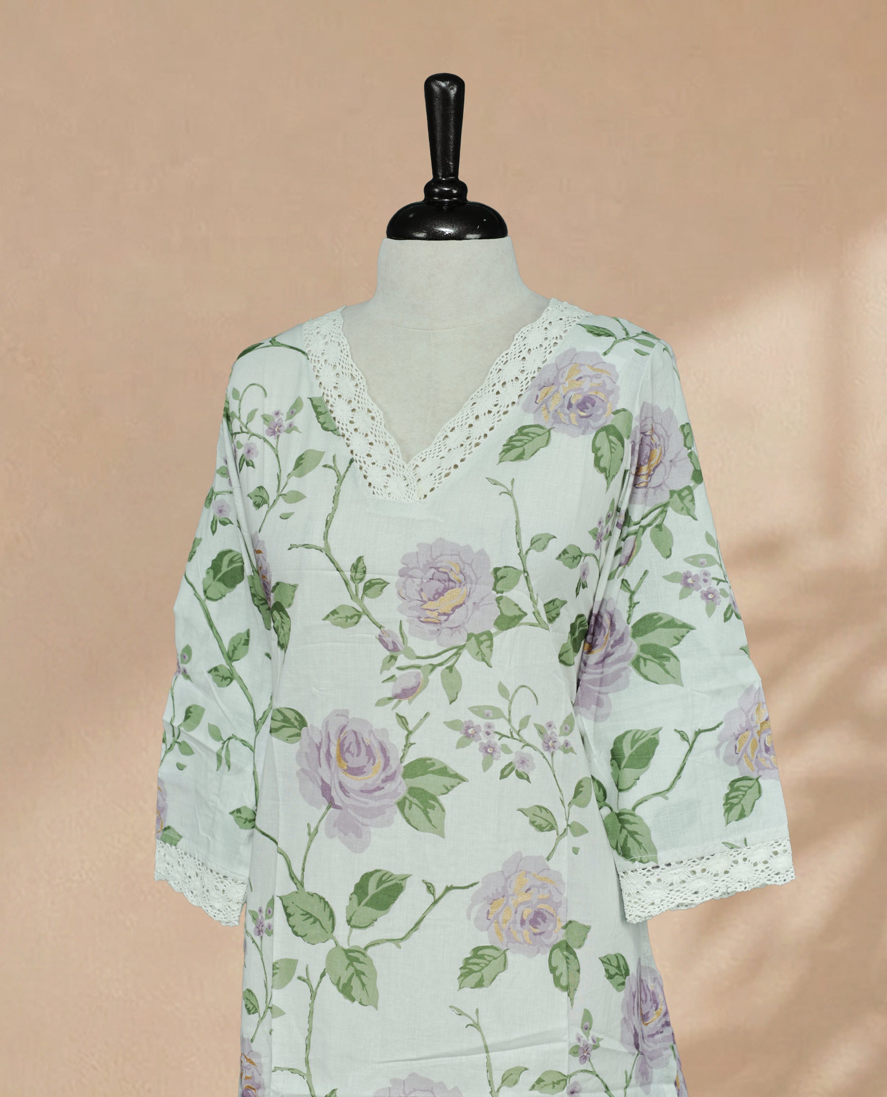 Off White Kurti featuring a delicate floral print with lavender roses and green leaves, a V-shaped neckline adorned with white lace detailing, and 3/4 sleeves finished with matching lace borders