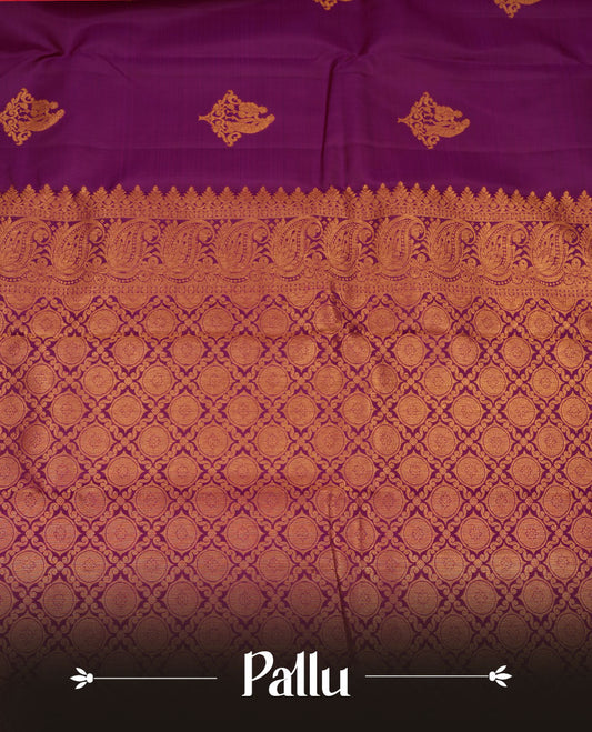 Rich magenta colour pure traditional Kancheepuram silk saree adorned with an elegant zari motif on the body, complemented by a grand gold zari woven border with intricate traditional patterns, paired with a matching blouse piece.