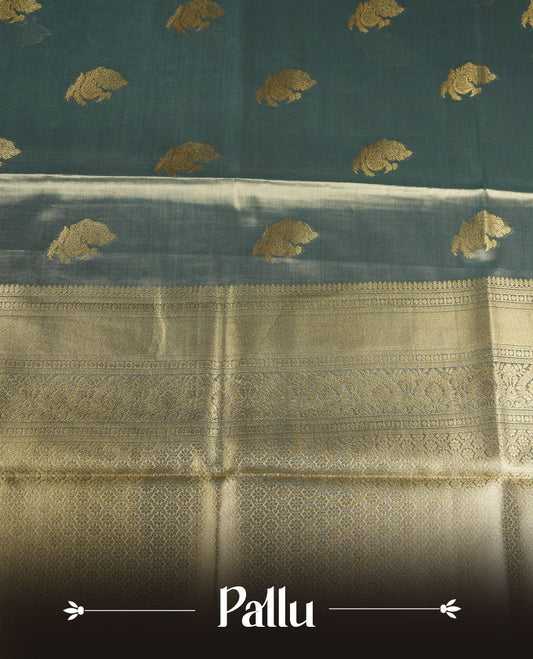 Dual tone teal and gold colour tissue brocade saree featuring antique gold zari motifs on the body with a rich traditional zari border and pallu, paired with a matching blouse piece.