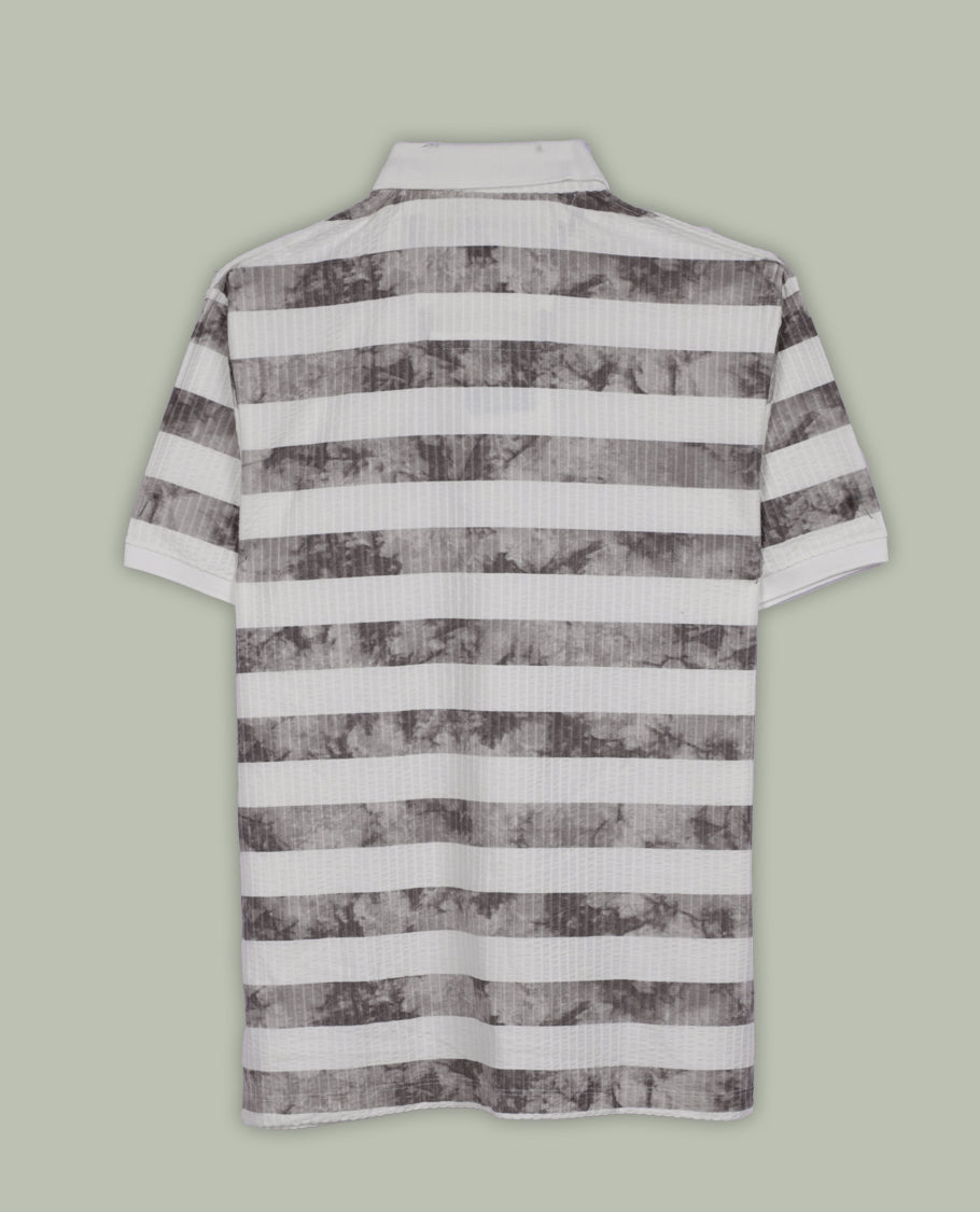 Off white and grey colour striped polo T shirt featuring a collared neck with button placket, half sleeves, and a textured fabric design, enhanced with a front chest patch that adds a trendy casual vibe.