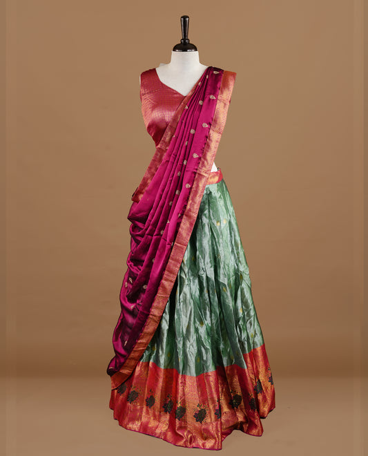 Green colour Half saree featuring green colour skirt with contrast magenta colour traditional border, paired with matching stitched blouse, matching dupatta.