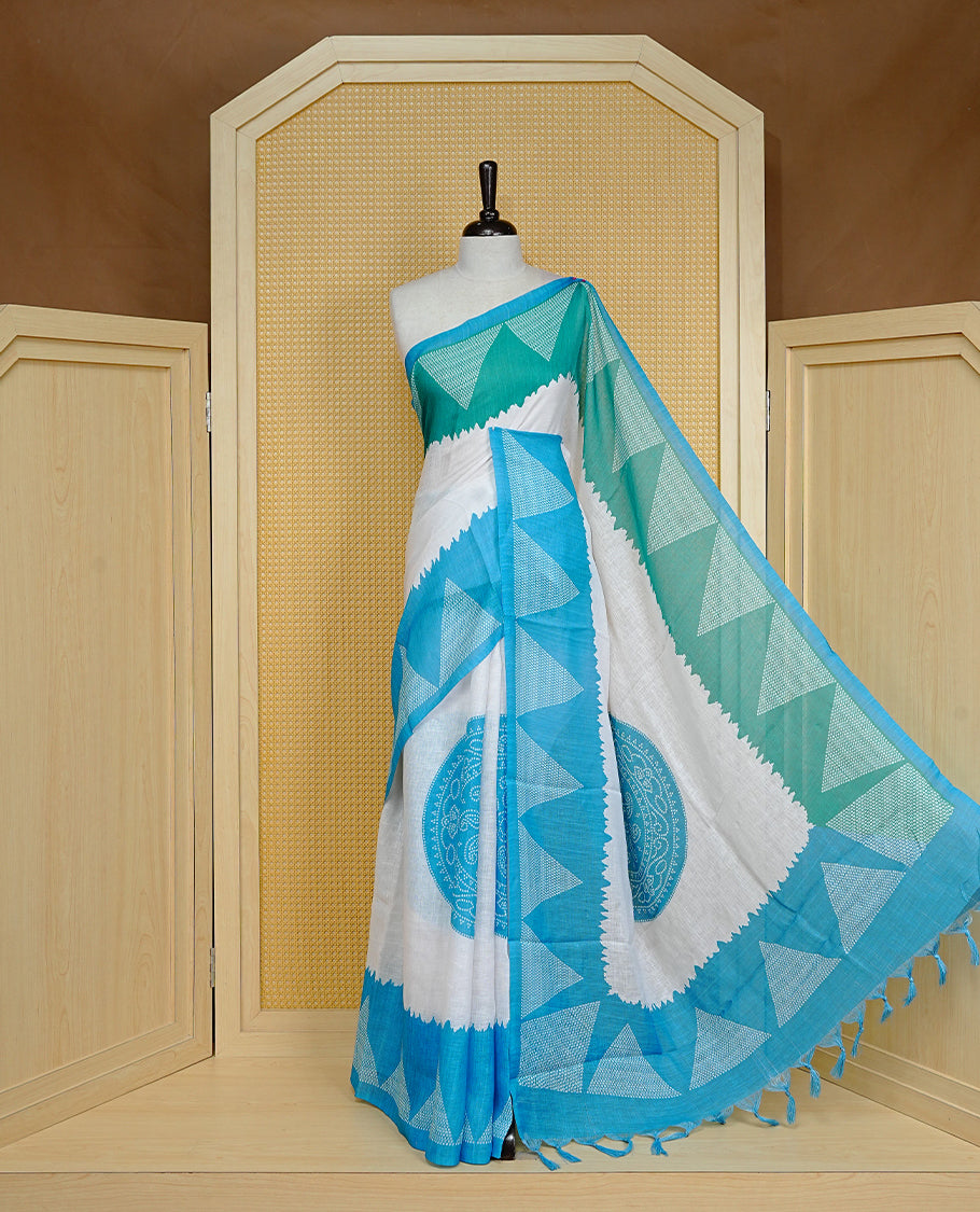 Cream colour semi linen saree featuring Blue Ajrakh pattern print on body, complemented by contrast Green colour with same pattern print Blue border, comes with matching blouse piece.