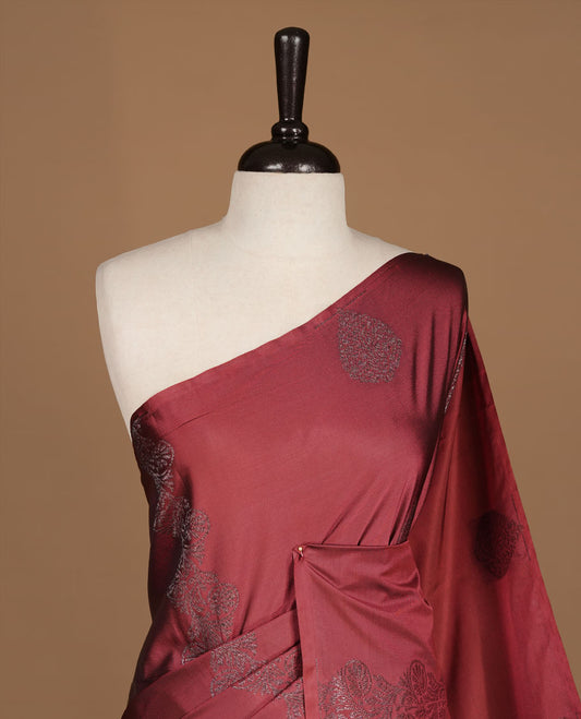 Maroon colour soft silk saree features a sleek borderless design with intricate antique zari motifs, flowing into a striking contrast blue pallu and a matching blouse piece.