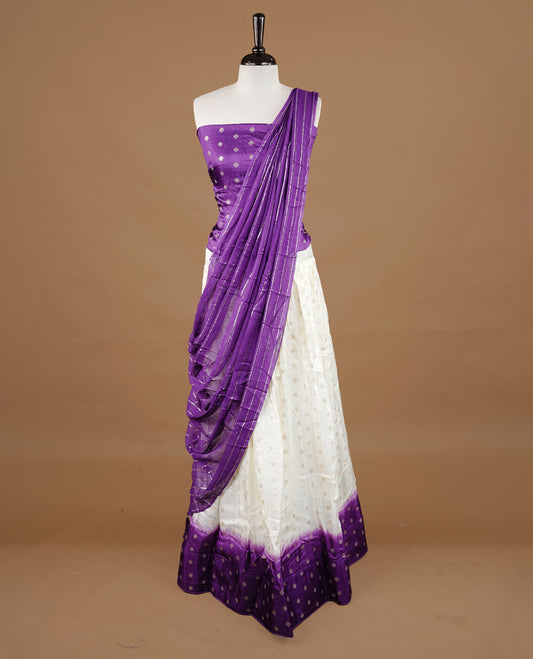 Off white colour semi stitched half saree featuring elegant zari buttas on the body, paired with a contrast purple border and matching striped dupatta,paired with matching blouse piece.