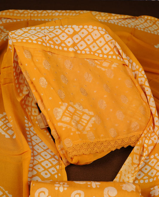 Yellow orange colour churidar material featuring elegant gold butta work on the front panel, paired with a printed dupatta and matching bottom.