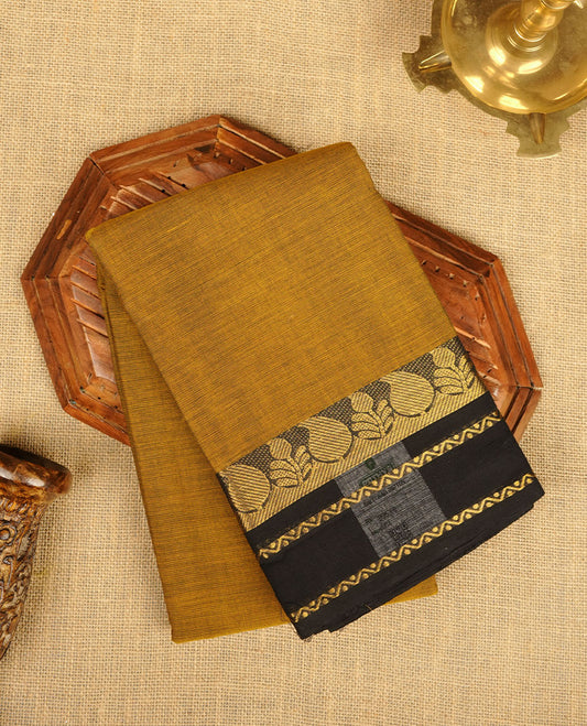 Dark mustard yellow colour chettinad cotton saree featuring plain body, paired with a black colour traditional gold zari border without blouse.