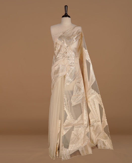 Cream colour pure net organza saree featuring gold geometric pattern on body, featuring scalp designed border, paired with matching blouse piece