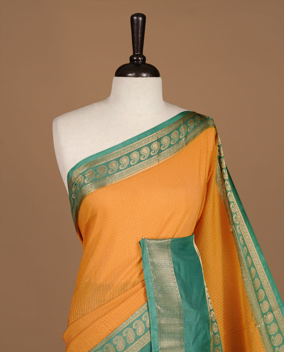 Mustard colour semi georgette saree featuring gold zari check pattern on body, complemented by contrast green colour with zari border, paired with matching blouse piece.