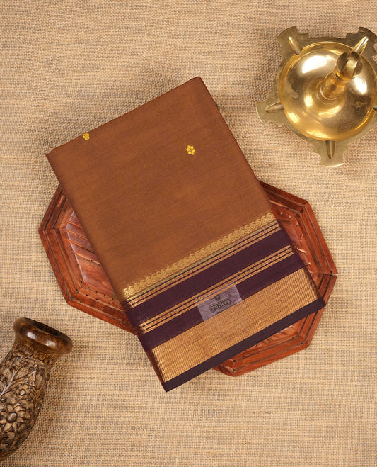 Brown colour chettinad cotton saree featuring small gold zari buttas on body highlighting contrast dark chocolate colour with gold zari traditional border, pallu and paired with matching blouse piece.