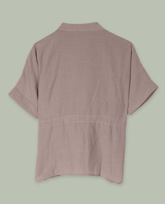 Taupe short-sleeve top with V-slit band neckline, contrast white crochet motif on one side, and adjustable drawstring detail at the waist