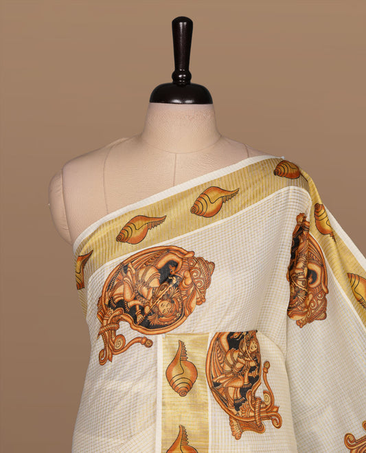 Off white color kerala cotton saree featuring gold zari check on body, complemented by, gold zari with krishna printed border, paired with matching blouse piece.