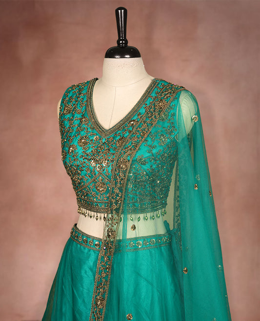 Green colour lehenga set with stitched sleeveless Antique thread embroidered & beats worked  blouse featuring sheer neckline, matching stitched flared lehenga, and plain sheer dupatta.