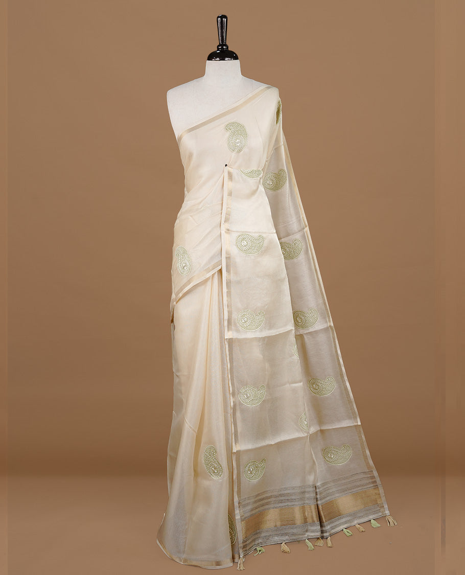 Cream colour Tussar saree featuring Light green colour Mango pattern with chikankari embroidery work, highlighting gold zari simple border, paired with matching unstitched blouse.
