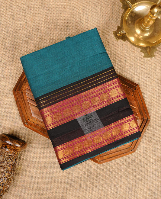 Teal colour chettinad cotton saree featuring plain body, contrast black and red colour with traditional gold zari border paired with matching blouse.