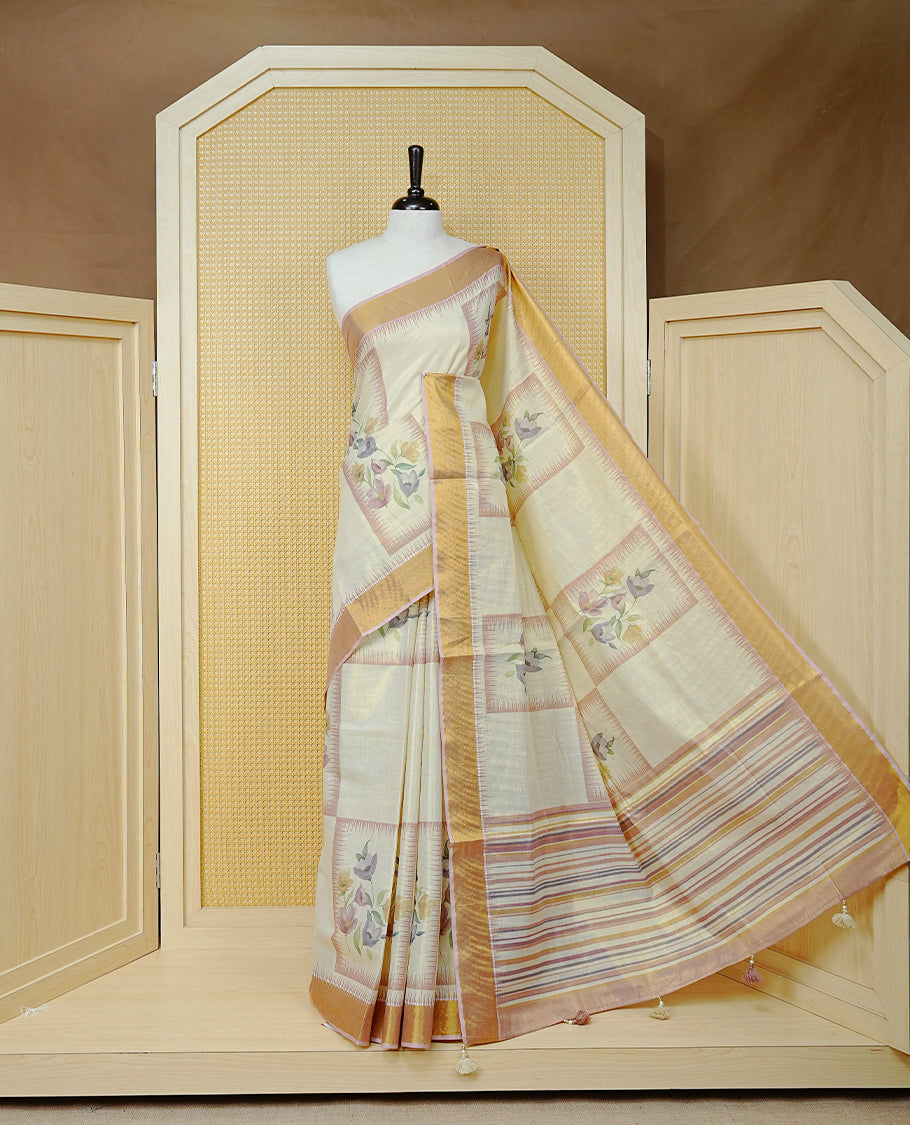 Cream Colour Tissue  Kerala Saree Featuring Floral Prints in a Stylish Rectangle Pattern On Body, Enhanced with a Gold Zari Border and a Multicoloured Striped Pallu. Finished with Elegant Tassels and Paired with a Matching Blouse Piece.